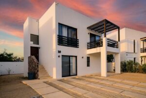 Cabo Luxury Casa Mex-Agaves Situated within the Casa Mexicana - Agaves community, this thoughtfully designed three-bedroom residence offers a functional and well-planned layout. The main level features a bedroom with an en-suite bathroom and walk-in closet, ideal for guests, multigenerational living, or those seeking stair-free access.A spacious outdoor terrace on the first floor, surrounded by tropical landscaping, provides a serene setting for both relaxation and entertaining. With multiple seating areas, it stands out as a unique feature within Casa Mexicana. The upper level includes two additional bedrooms, each with en-suite bathrooms and walk-in closets, along with the home's main living and kitchen areas. The indoor spaces are seamlessly connected to an additional terrace, enhancing the home's indoor-outdoor living appeal.Additional features include a dedicated laundry area, a two-car garage, and accordion-style hurricane shutters, combining comfort with practicality and peace of mind. – 521 ISLA NATIVIDAD, Cabo Corridor, BS