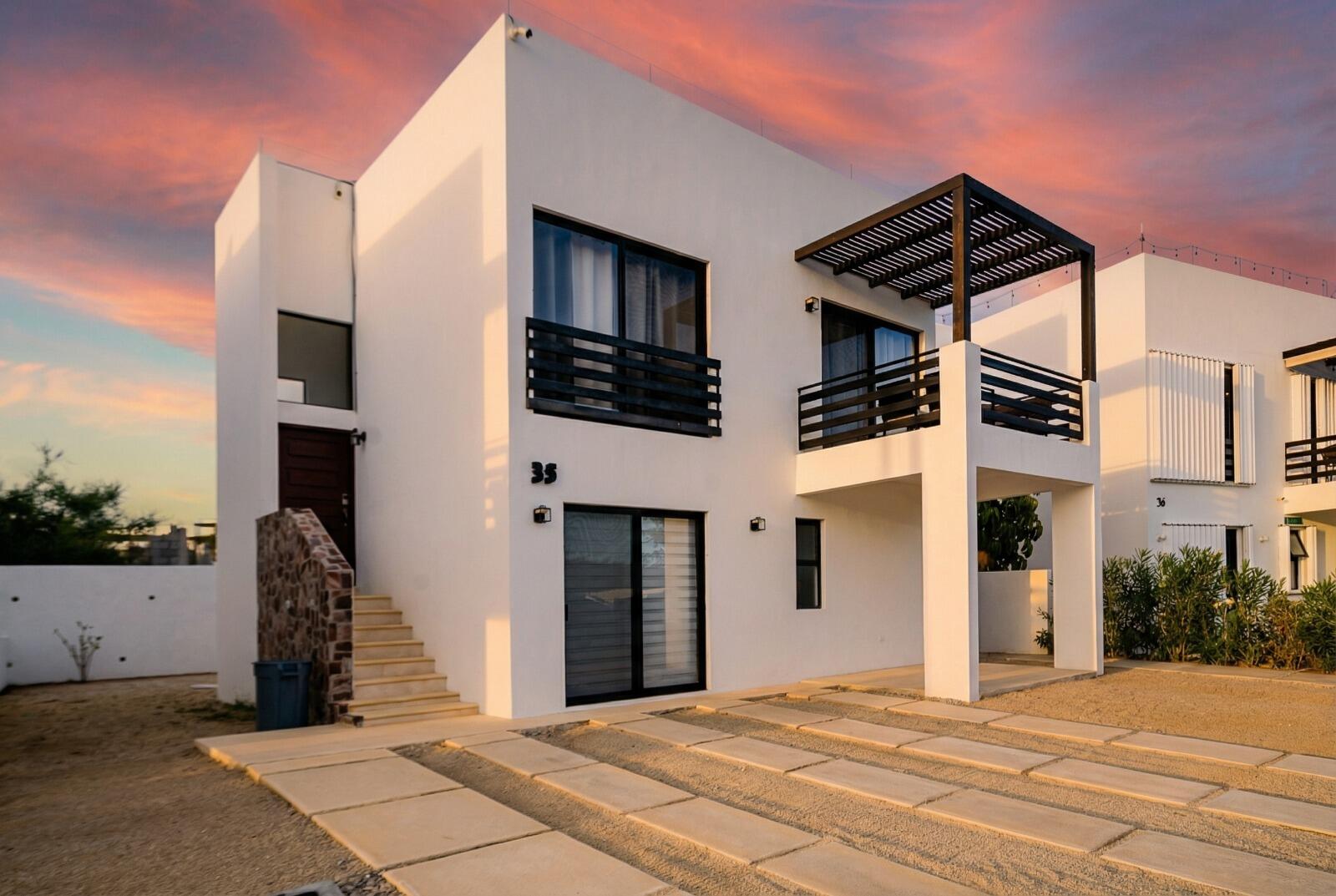 Cabo Luxury Casa Mex-Agaves Situated within the Casa Mexicana - Agaves community, this thoughtfully designed three-bedroom residence offers a functional and well-planned layout. The main level features a bedroom with an en-suite bathroom and walk-in closet, ideal for guests, multigenerational living, or those seeking stair-free access.A spacious outdoor terrace on the first floor, surrounded by tropical landscaping, provides a serene setting for both relaxation and entertaining. With multiple seating areas, it stands out as a unique feature within Casa Mexicana. The upper level includes two additional bedrooms, each with en-suite bathrooms and walk-in closets, along with the home's main living and kitchen areas. The indoor spaces are seamlessly connected to an additional terrace, enhancing the home's indoor-outdoor living appeal.Additional features include a dedicated laundry area, a two-car garage, and accordion-style hurricane shutters, combining comfort with practicality and peace of mind. for sale